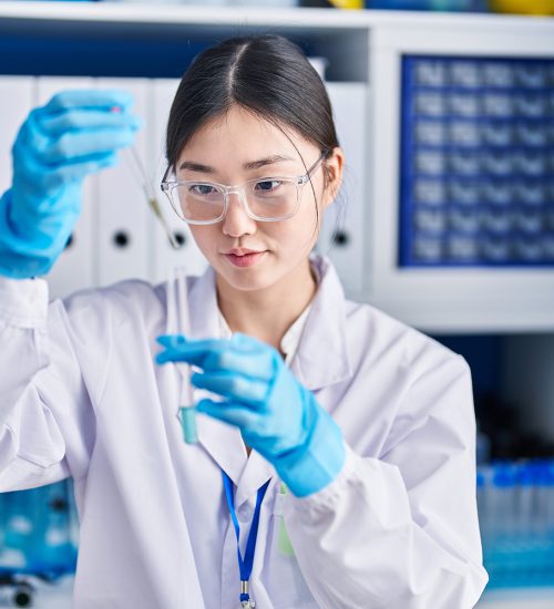 Chinese woman scientist pouring liquid on test tube at laboratory Chinese woman scientist pouring liquid on test tube at laboratory